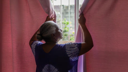 Overheating Woman Closing Curtains